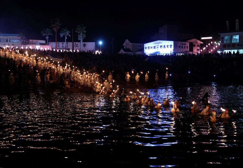 ‘Ama’ female free divers, who harvest sea life from the ocean, lead volunteers as they swim with torches during Shirahama Ama matsuri in Minamiboso, Chiba Prefecture, Japan July 20, 2024. — Reuters pic