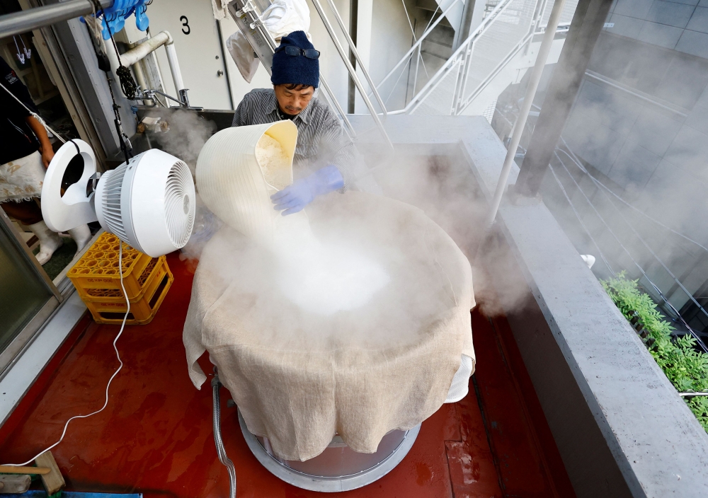 Yoshimi Terasawa, chief brewer at Tokyo Port Brewing, works to steam rice as a part of the sake brewing process at the brewery in Tokyo July 9, 2024. — Reuters pic