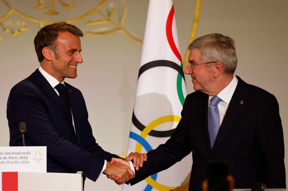 France's President Emmanuel Macron (left) shakes hands with International Olympic Committee (IOC) President Thomas Bach during a reception for international journalists accredited for the Paris 2024 Olympic Games at the Elysee Presidential Palace, in Paris on July 22, 2024, ahead of Paris 2024 Olympic and Paralympic games.