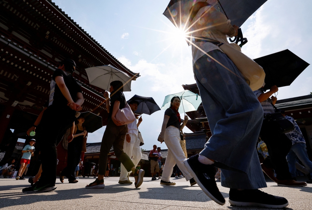 Passersby holding umbrellas walk under a strong sunlight at the Sensoji temple as Japanese government issued heat stroke alerts in 39 of the country's 47 prefectures in Tokyo July 22, 2024. — Reuters pic