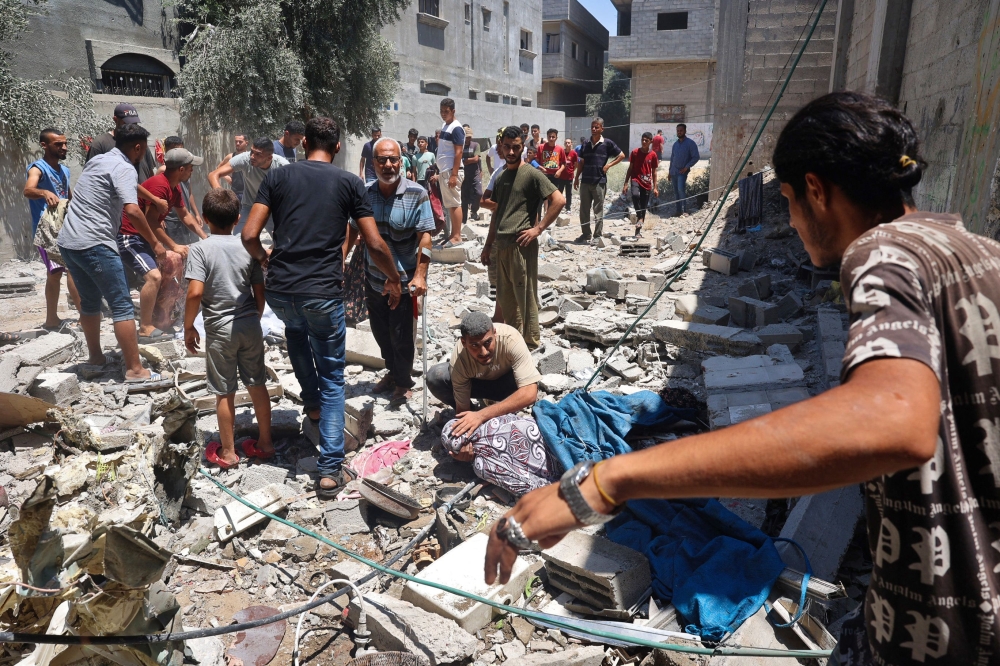 A man comforts an woman injured during Israeli bombardment at al-Bureij refugee camp in the central Gaza Strip yesterday. — AFP pic