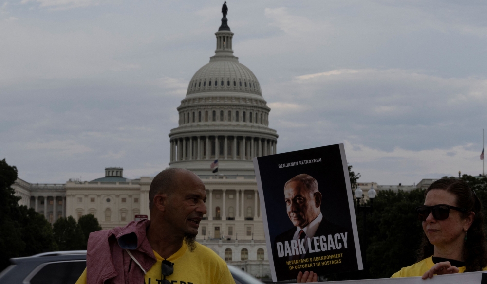A demonstrator holds a banner with a portrait of Israeli Prime Minister Benjamin Netanyahu as families of Israeli hostages gather ahead of his address to a joint meeting of Congress, at the National Mall in Washington July 23, 2024. — Reuters pic  