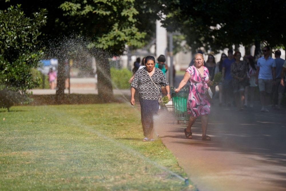 People cool off nearby sprinklers at Retiro Park during the second day of the heatwave, in Madrid, Spain, July 25, 2024. — Reuters pic