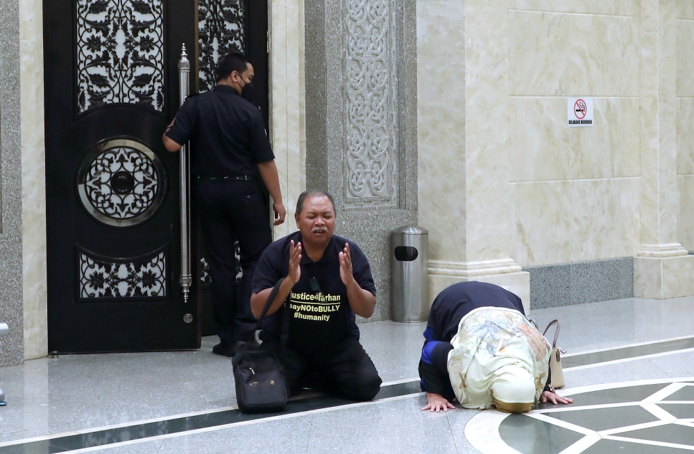 The father of murder victim and former Universiti Pertahanan Nasional Malaysia (UPNM) student Zulfarhan Osman Zulkarnain, Zulkarnain Idros (left), and his wife Hawa Osman, prostrate in gratitude after the Court of Appeal sentenced six former UPNM students to death by hanging at the Court of Appeal, Palace of Justice in Putrajaya, July 23, 2024. — Bernama pic 