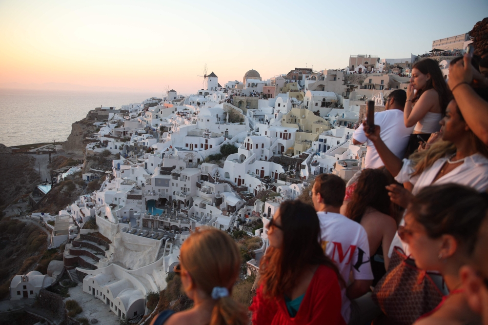 Tourists wait for the sunset in the village of Oia on the Greek island of Santorini on July 20, 2024. — AFP pic