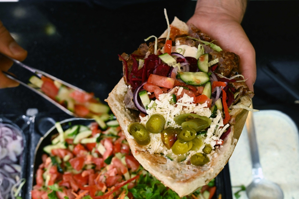 An employee prepares a doner with meat from a kebab skewer in a doner restaurant in the city centre of Dortmund July 26, 2024. — AFP pic