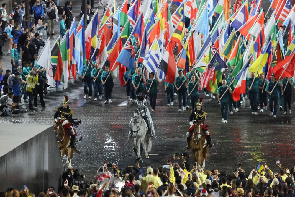 Floriane issert, a Gendarmerie non-commissioned officer of the National Gendarmerie, carries the Olympic flag as she rides on Pont D’iena during the opening ceremony of the Paris 2024 Olympic Games in Paris on July 26, 2024. — Reuters  pic