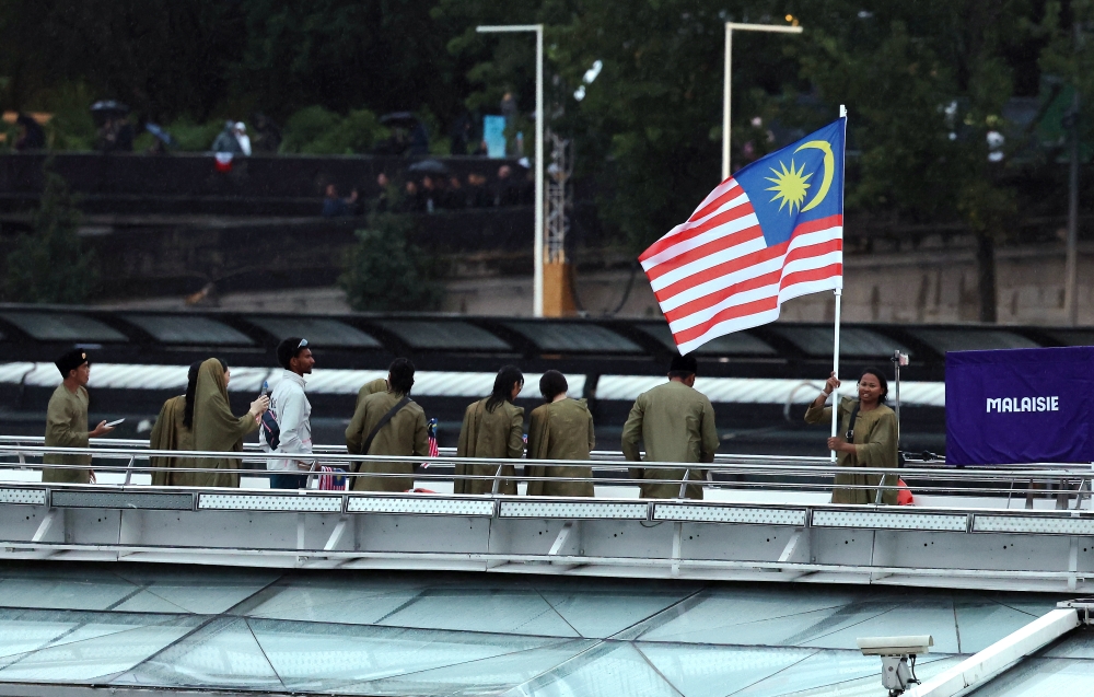 Malaysia’s Chef de Mission for the 2024 Paris Olympics, Datuk Hamidin Mohd Amin, along with Malaysia’s (Jalur Gemilang) flag-bearers, diving athlete Betrand Rhodic Lises and sailor Nur Shazrin Mohamad Latif, together with the national contingent’s athletes and officials, during the opening ceremony of the Paris 2024 Olympic Games on the River Seine, July 26, 2024. — Bernama pic 