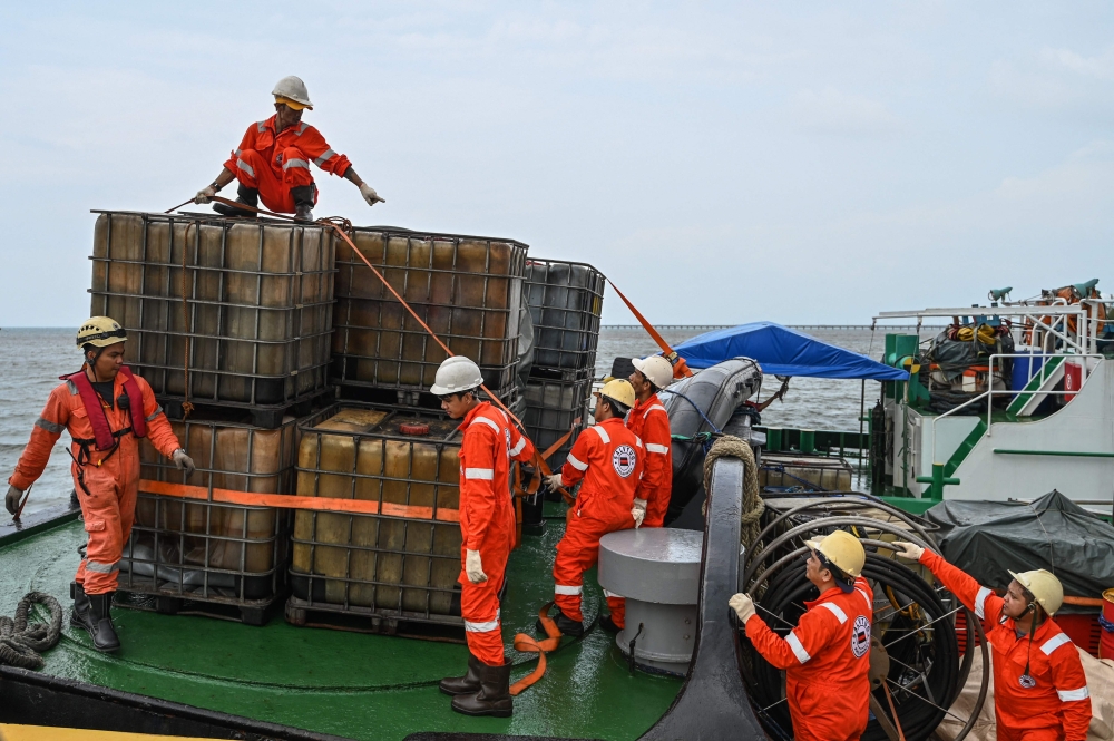 The crew of a private company secure containers to be used in the oil spill response, at a port in Limay, Bataan, the Philippines, on July 26, 2024. — AFP pic 