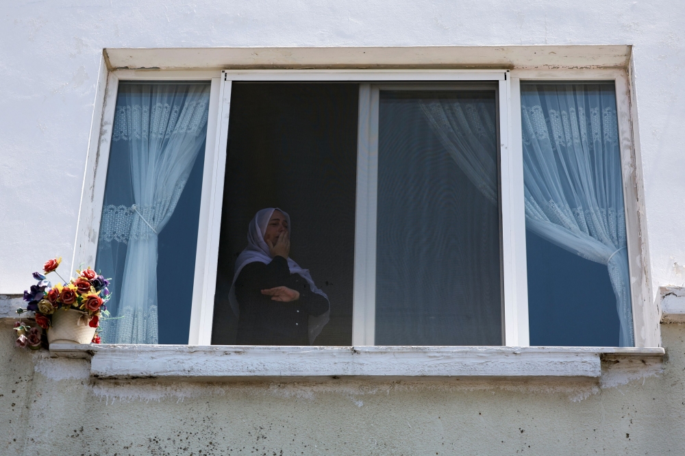 A woman reacts, as she looks through a window, on the day of the funeral of children who were killed at a soccer pitch by a rocket fired from Lebanon, in Majdal Shams, a Druze village in the Israeli-occupied Golan Heights, July 28, 2024. — Reuters pic