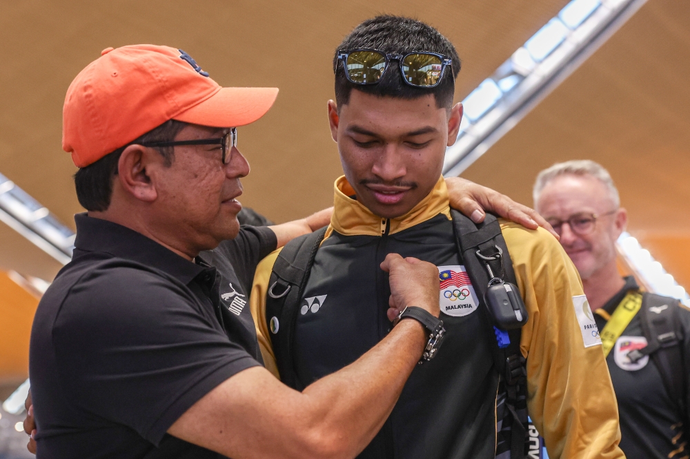 National sprinter Muhammad Azeem Fahmi shared a moment with his father Fahmi Tajuid before departing for the 2024 Paris Olympics at Kuala Lumpur International Airport (KLIA) yesterday. — Bernama pic