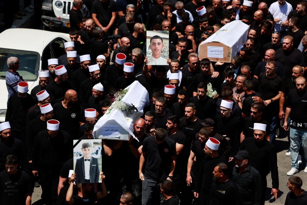Mourners carry coffins, during the funeral of children who were killed at a football pitch by a rocket fired from Lebanon, in Majdal Shams, a Druze village in the Israeli-occupied Golan Heights, July 28, 2024. — Reuters pic 