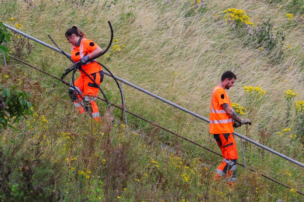 A SNCF railway worker carries cable wires at the site where vandals targeted France's high-speed train network with a series of coordinated actions that brought major disruption, ahead of the Paris 2024 Olympics opening ceremony, in Croisilles, northern France on July 26, 2024. — Reuters pic