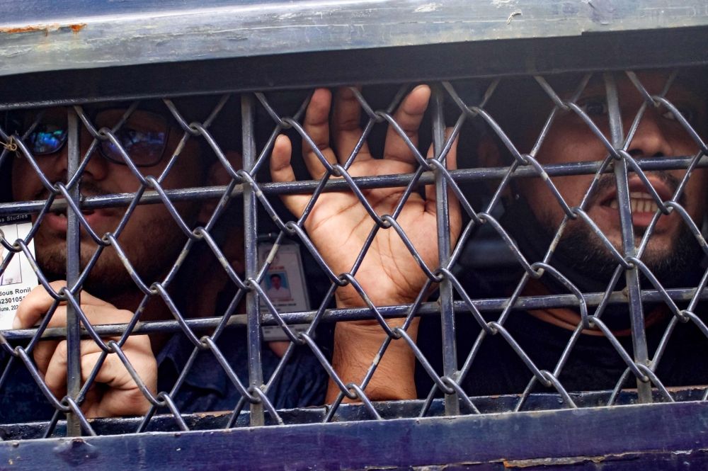 Students detained over rallying against quotas in government jobs, look out from a prison van following their arrest by Bangladesh police personnel, along the street in Dhaka July 29, 2024. — AFP pic