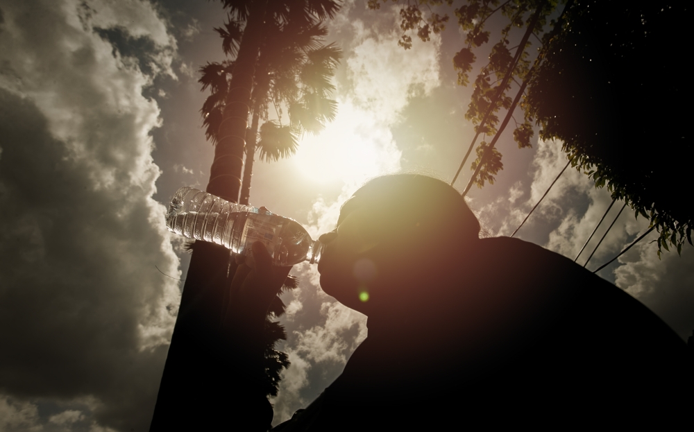 The public is advised to keep hydrated when carrying out outdoor activities. If needed, use a hat or a non-transparent umbrella to protect the skin from the heat. — Picture by Raymond Manuel