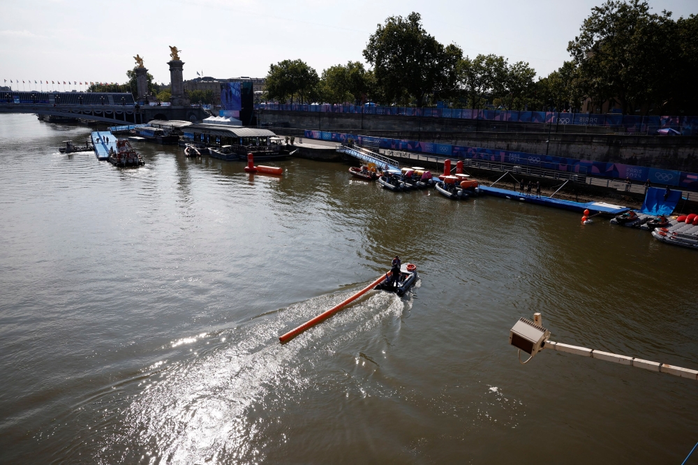 General view of the river Seine and Alexander III Bridge as workers remove a buoy after Triathlon training was cancelled amid water quality concerns. — Reuters pic