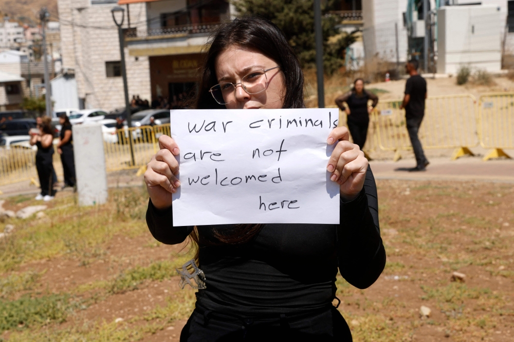 A woman holds a poster as she and others demonstrate against Israeli Prime Minister Benjamin Netanyahu during his visit to the Druze village of Majdal Shams in the Israel annexed Golan Heights on July 29, 2024. — AFP pic