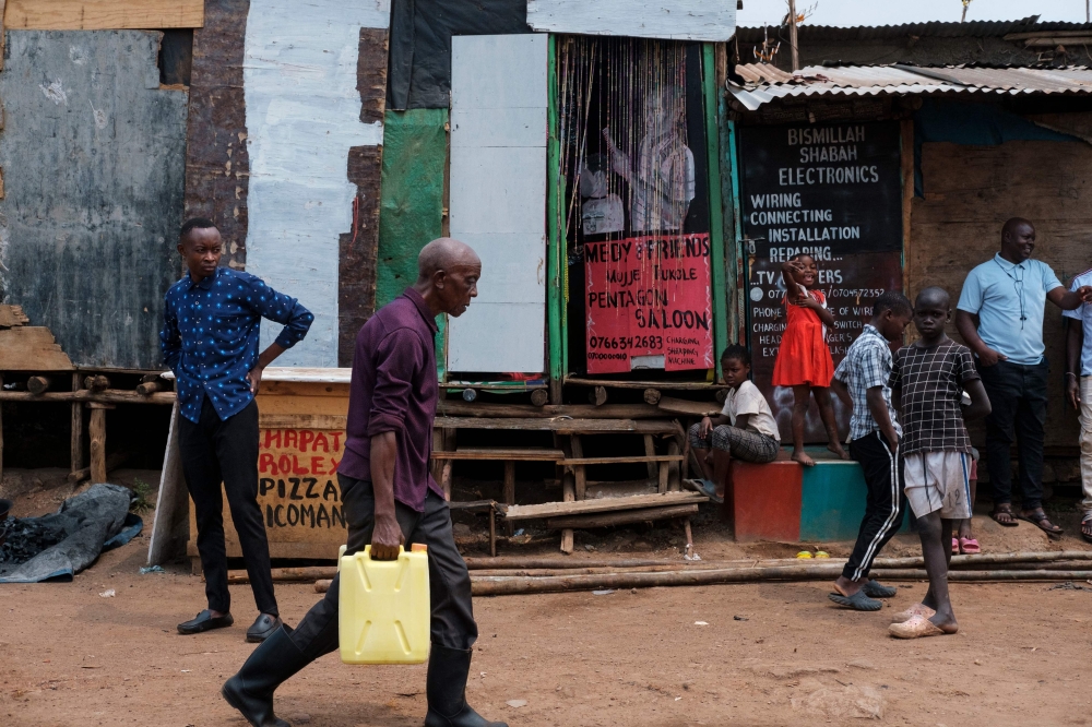 An elderly man carries a jerrycan of water in the Namuwongo slum in Kampala on July 20, 2024. — AFP pic