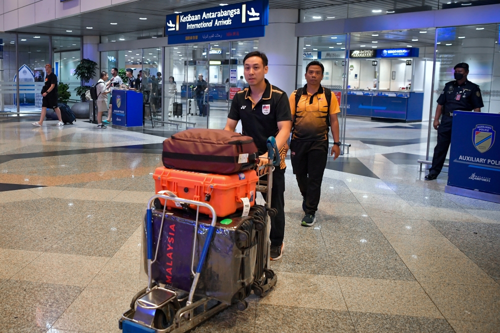 National shooter Johnathan Wong along with shooting coach Mohd Firdaus Abd Rahim (second, left) arrived at Kuala Lumpur International Airport here today. — Bernama pic