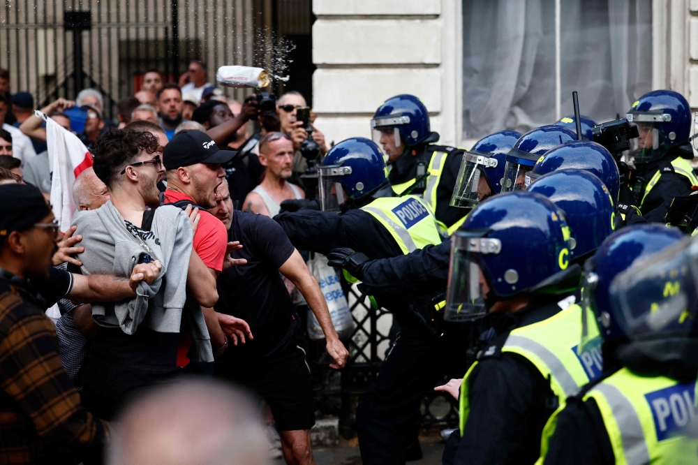 A can of lager flies through the air as protestors remonsrate with police officers during the ‘Enough is Enough’ demonstration on Whitehall, outside the entrance to 10 Downing Street in central London on July 31, 2024, held in reaction the government’s response to the fatal stabbings in Southport on July 29. — AFP pic 