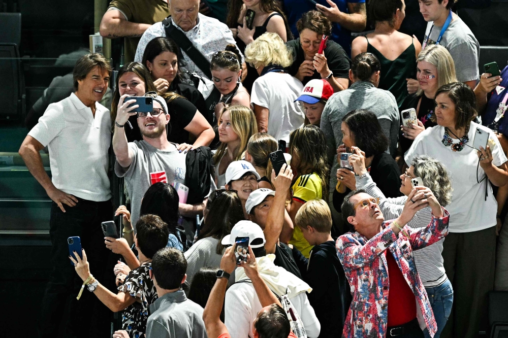 Tom Cruise taking selfies with fans. — AFP pic
