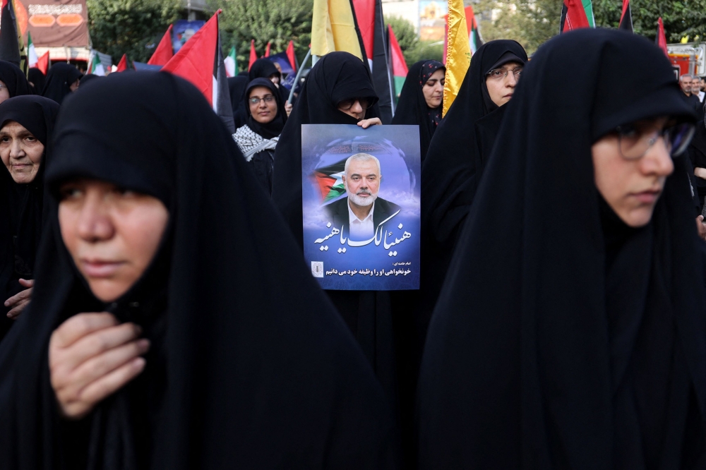 A person holds a poster of Palestinian group Hamas’ leader Ismail Haniyeh, during an anti-Israel gathering following his killing amid the ongoing conflict between Israel and Hamas, in Tehran, Iran July 31, 2024. — Majid Asgaripour/WANA (West Asia News Agency) handout pic via Reuters 