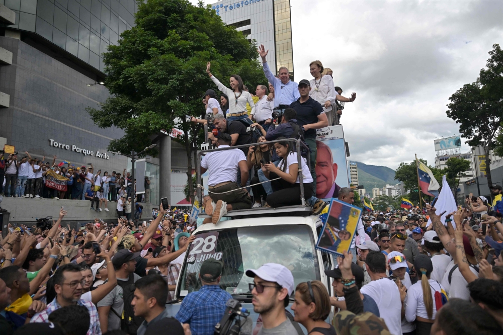 Venezuelan opposition leader Maria Corina Machado (centre, left) and opposition presidential candidate Edmundo Gonzalez Urrutia (centre, right) greet supporters during a rally in front of the United Nations headquarters in Caracas July 30, 2024. — AFP pic