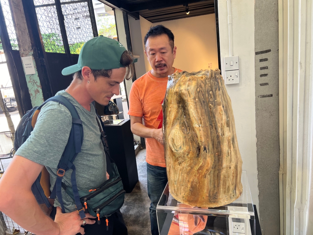Ceramic artist James Seet (right) explaining the concept behind his work to a visitor at his ‘Echoes of Eden’ exhibition. — Picture by Opalyn Mok 