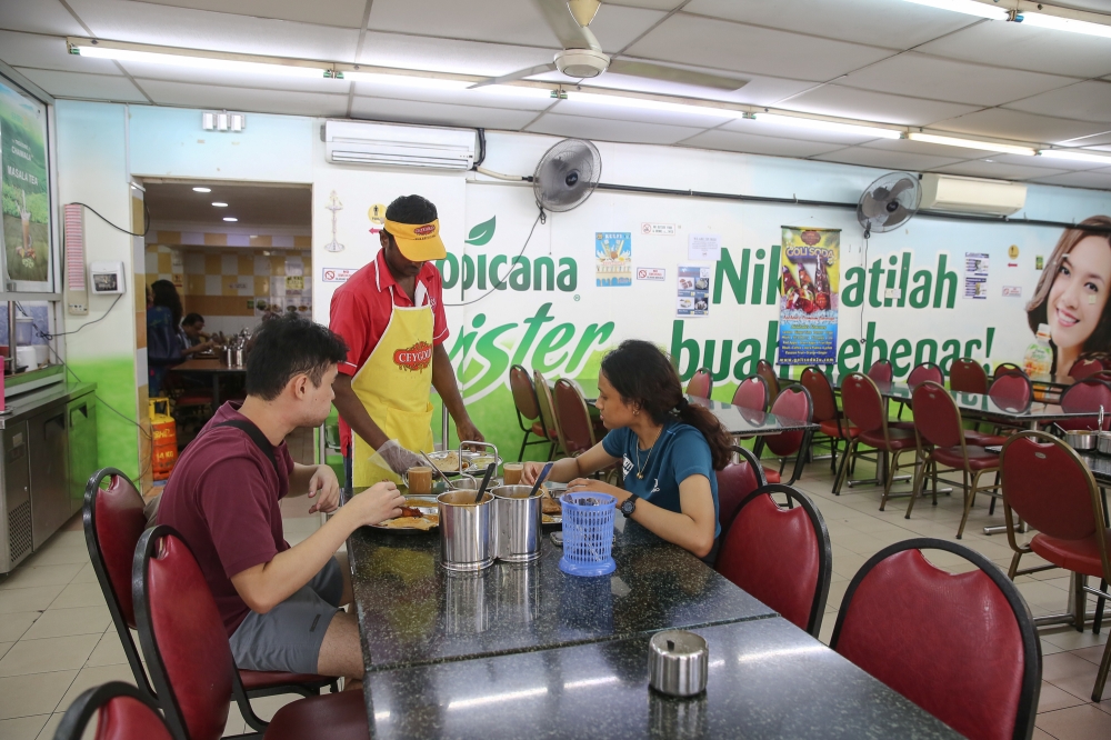 A worker serves food at a Sri Seenu Restaurant in Petaling Jaya July 8, 2024. A total of 136,453 food and beverage (F&B) services establishments were operating in 2022 with gross output value of RM99.0 billion compared with 167,490 establishments valued RM66.4 billion in 2015, according to the Department of Statistics Malaysia. — Picture by Yusof Mat Isa