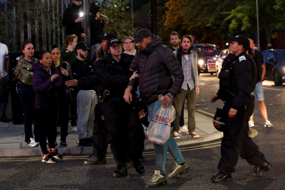 A police officer holds a man after he argues with people on the sidewalk as people gather against an anti-immigration protest in Liverpool August 7, 2024. — Reuters pic
