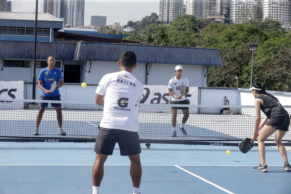Pickleball is played using a racket or paddle in which two players (singles) or four players (doubles) use to hit a perforated, hollow plastic ball over a net until one side is unable to return the ball or commits a rule infraction. — Picture by Sayuti Zainudin