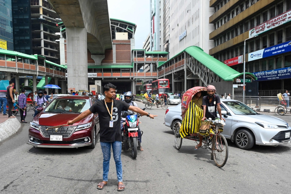 A Bangladeshi student controls traffic in capital city Dhaka as national police went on strike on August 7, 2024. — AFP pic