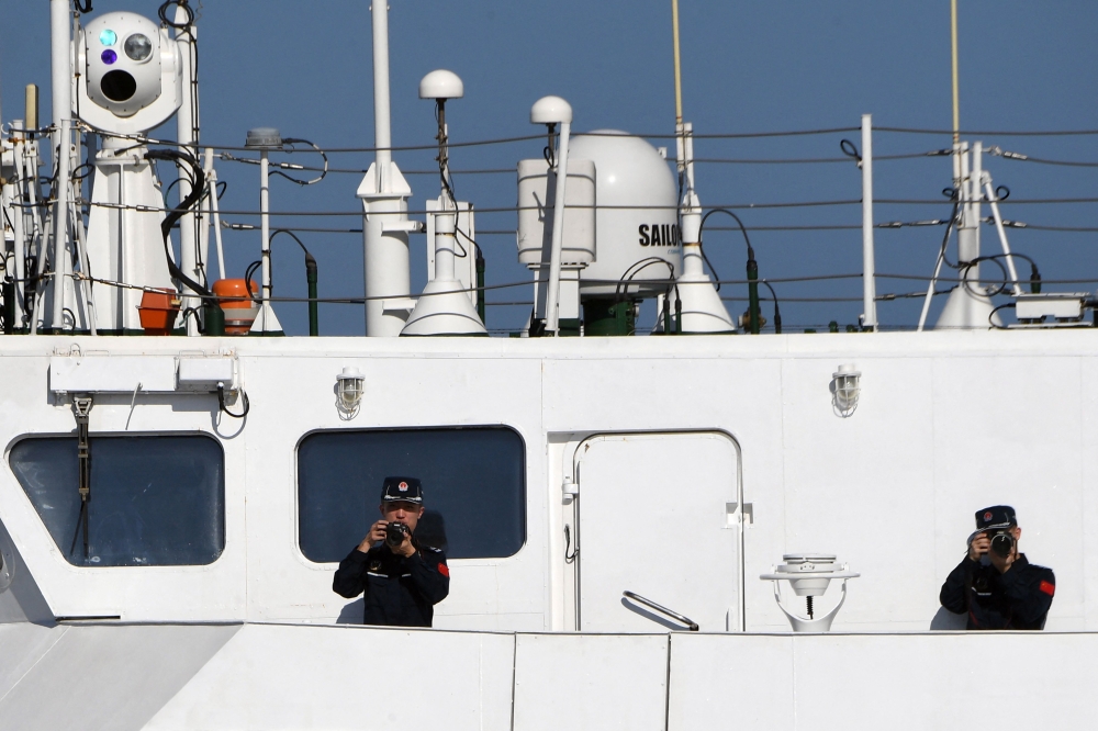 This photo taken on February 15, 2024 shows Chinese coast guard personnel taking photographs of the Philippine Bureau of Fisheries and Aquatic Resources (BFAR) ship BRP Datu Tamblot while shadowing the Philippine vessel near the China-controlled Scarborough Shoal, in the disputed waters of the South China Sea. — AFP pic