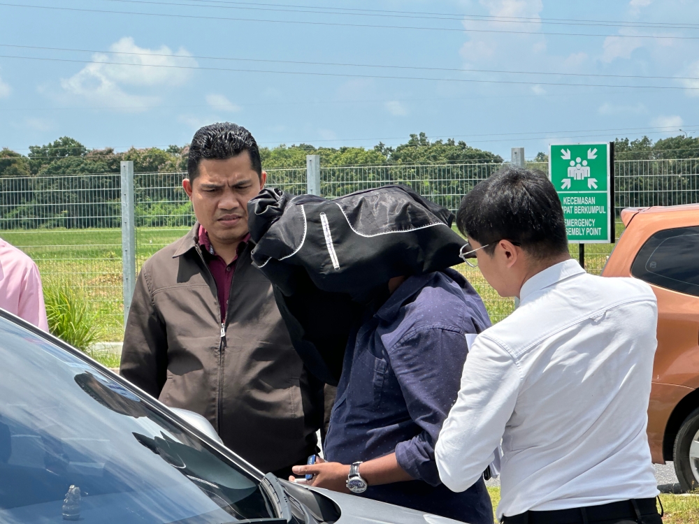 Poobalan a/l Krishnasamy (head covered) was allowed bail of RM10,000 with one surety for both charges and ordered to surrender his passport to the court and report himself at the nearest office of the Malaysian Anti-Corruption Commission (MACC) once a month. — Bernama pic 