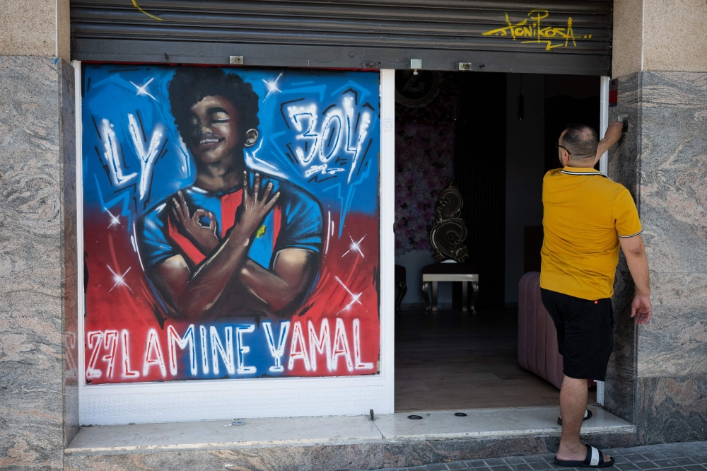 A man looks at a graffiti depicting Lamine Yamal in Rocafonda, the neighbourhood where Spain's forward grew up, in Mataro, 35km from Barcelona, on July 11, 2024. — AFP pic