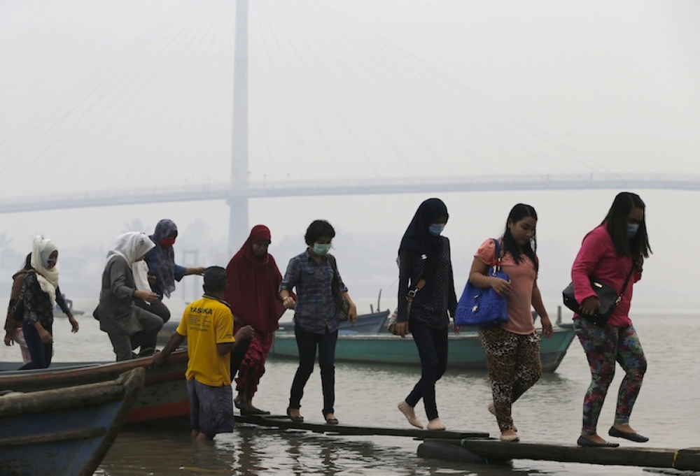 A file photograph shows Indonesian workers disembarking from a boat in Jambi, Sumatra. — Reuters pic