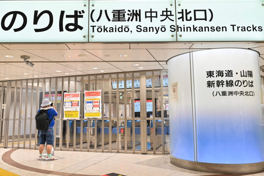 A traveller takes a photo of a sign posted on the closed doors of the high-speed bullet train, or ‘Shinkansen’, service informing passengers that it has been suspended due to severe weather warnings, at Tokyo Station in central Tokyo on August 16, 2024 as Typhoon Ampil barrels towards Japan's capital. — AFP pic