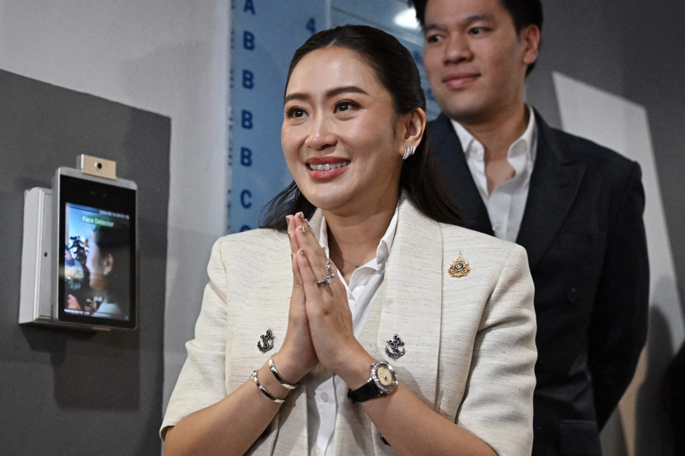 Pheu Thai party leader Paetongtarn Shinawatra, known by her nickname ‘Ung Ing’ and daughter of former prime minister Thaksin Shinawatra, greets members of the media at local news outlet Voice TV in front of her husband Pitaka Suksawat in Bangkok August 16, 2024. — AFP pic