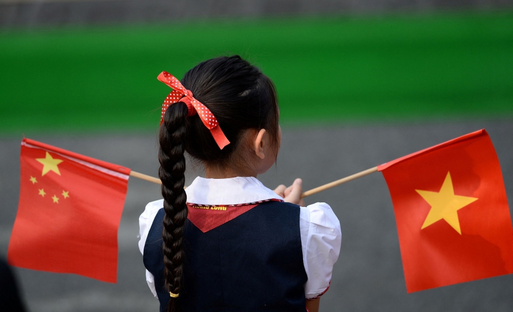 A Vietnamese pupil holds Vietnamese and Chinese flags before the welcoming ceremony at the Presidential Palace in Hanoi November 12, 2017. — Reuters pic