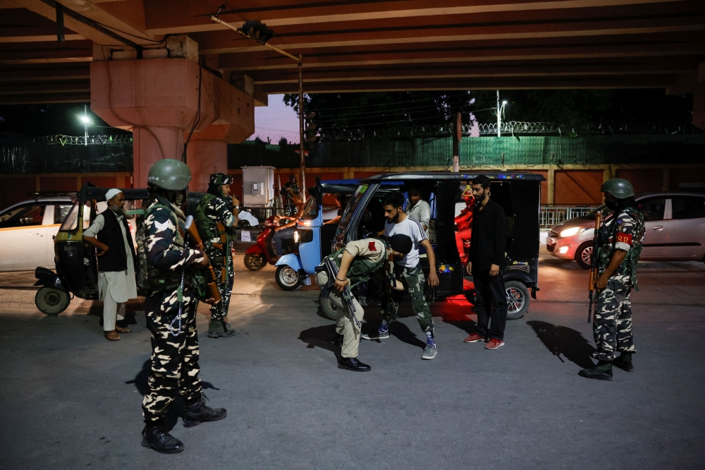 Indian security personnel frisk Kashmiri men near the venue for India's Independence Day celebrations in Srinagar August 14, 2024. — Reuters pic