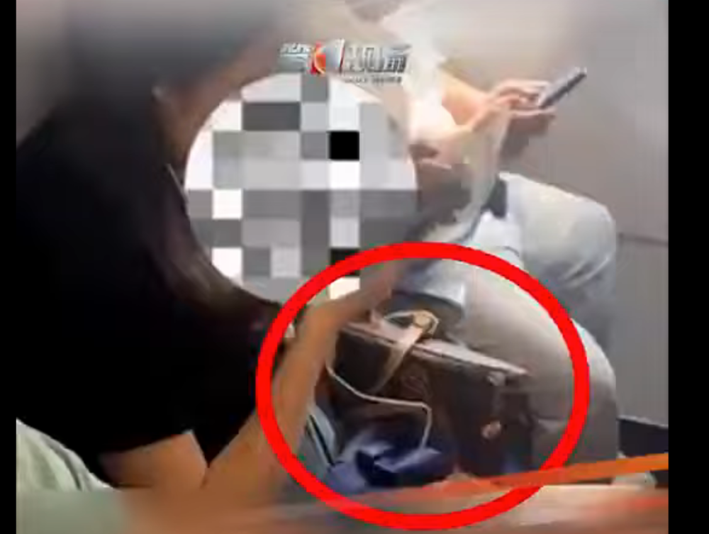 The woman's bag is seen tucked by her side as refused to stow it away during take-off.  — Screenshot from Youtube