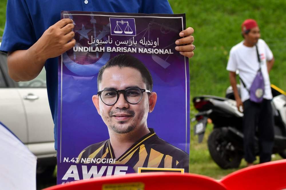 A Barisan Nasional supporter holds a poster of coalition candidate Mohd Azmawi Fikri Abdul Ghani outside Sekolah Kebangsaan Meranto in Gua Musang August 17, 2024, on polling day for the Nenggiri State Legislative Assembly by-election. — Bernama pic