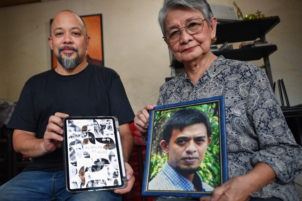 This photo taken on August 1, 2024 shows Edita Burgos ®ght), the mother of missing activist Jonas Burgos, holding a portrait of her vanished son while posing with her younger son, independent film director JL Burgos. — AFP pic