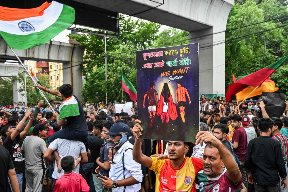 Supporters of arch-rival football club of the city East Bengal and Mohun Bagan shout slogans as police block their way during a protest march to condemn the rape and murder of a doctor in India's West Bengal state, in Kolkata on August 18, 2024. — AFP pic