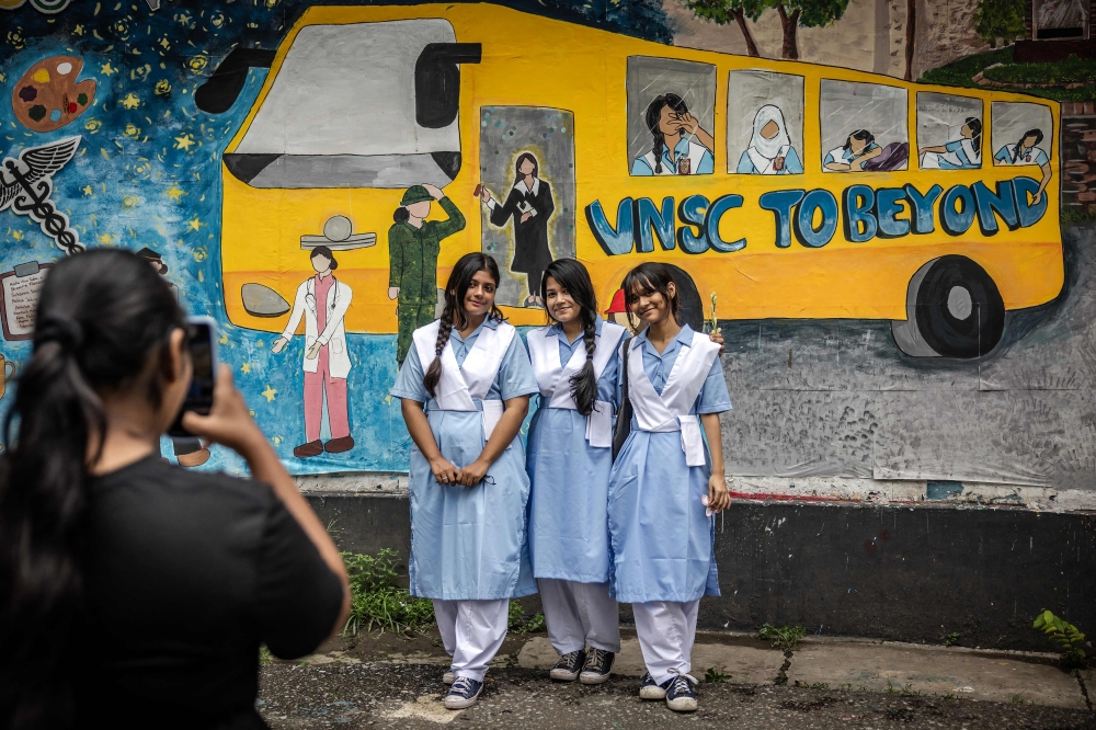College students take a photo in front of a mural while hanging out together for the first time in weeks during the reopening of schools after a long halt due to the violence surrounding anti-government protests that resulted in the resignation of Sheikh Hasina at the Viqarunnisa Noon School and College in Dhaka on August 18, 2024. — AFP pic