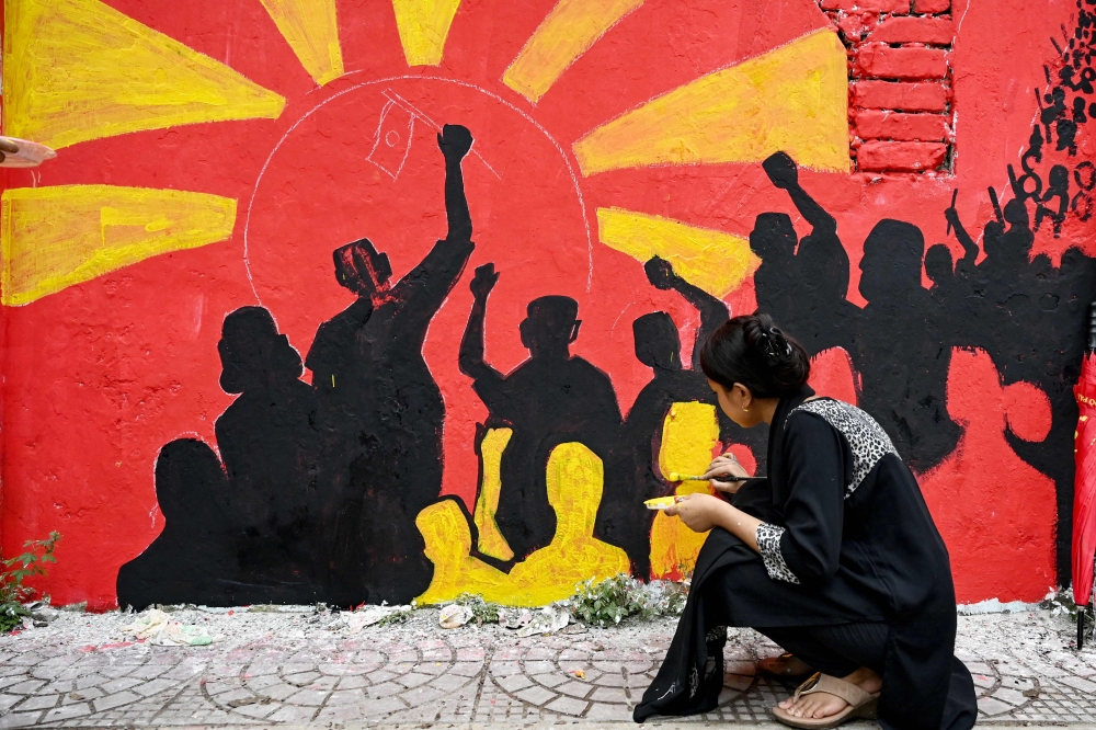 In this photograph taken on August 12, 2024, a college student paints graffiti on a wall at Dhaka university in the capital. — AFP pic