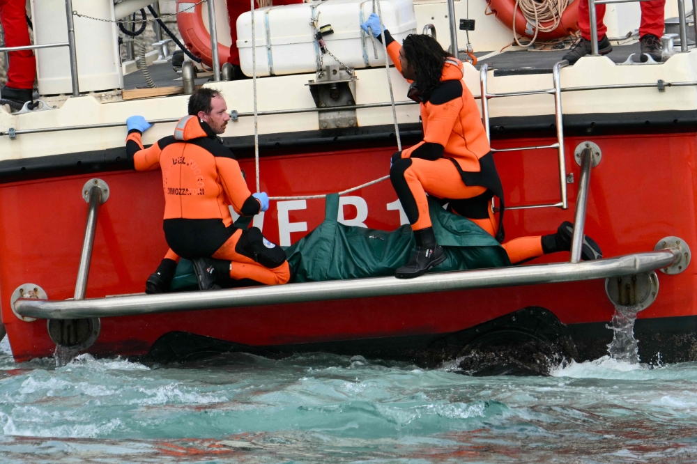 Divers of the Vigili del Fuoco, the Italian Corps. of Firefighters arrive with a body bag at the back of the boat in Porticello near Palermo. — AFP