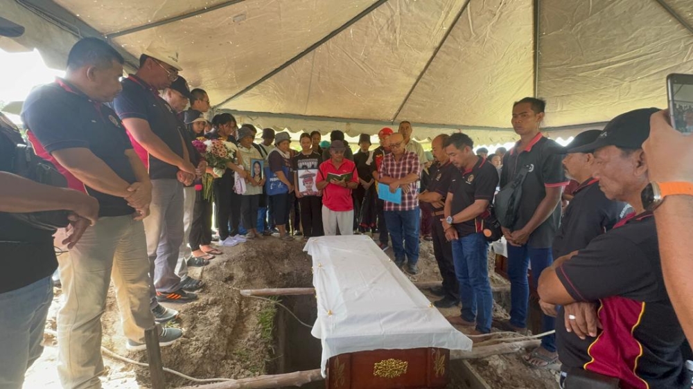 Committal prayers are said for Alasma before the coffin is lowered into her final resting place. — The Borneo Post pic