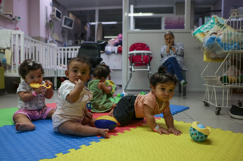 Palestinian triplets of Gaza-native Hanane Bayouk, Najmeh (left), Noor (centre)and Najoua play with another toddler, at the children's ward of the Al-Maqased Hospital in east Jerusalem July 31, 2024. — AFP pic