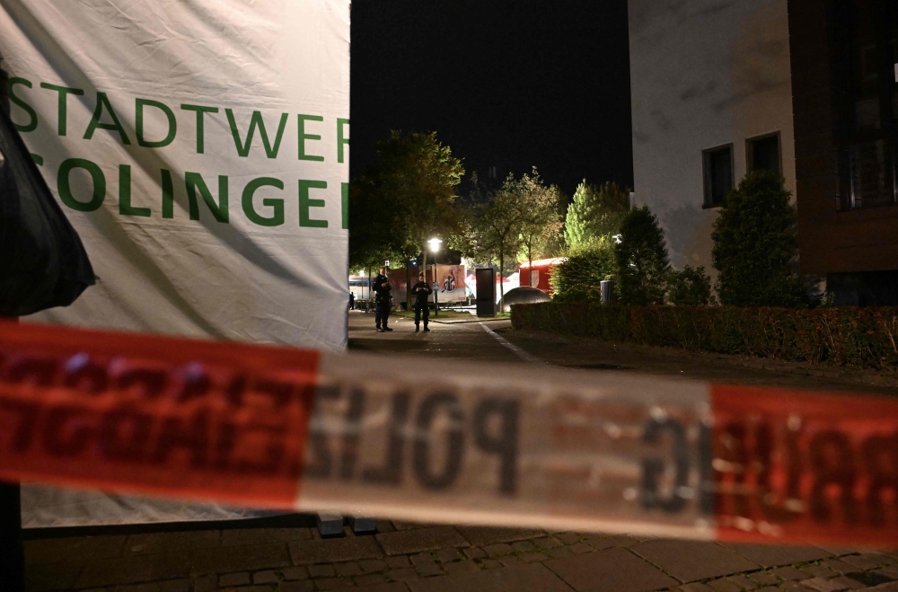 German police patrol a taped-off area in Solingen, western Germany where three people died, and several were wounded when a man went on a stabbing rampage as  the city celebrated its 650th anniversary. — AFP pic